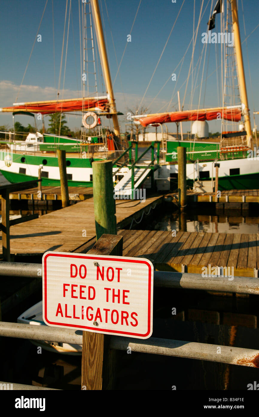"Do not feed alligators" sign on pier for historic sailboat, Historic