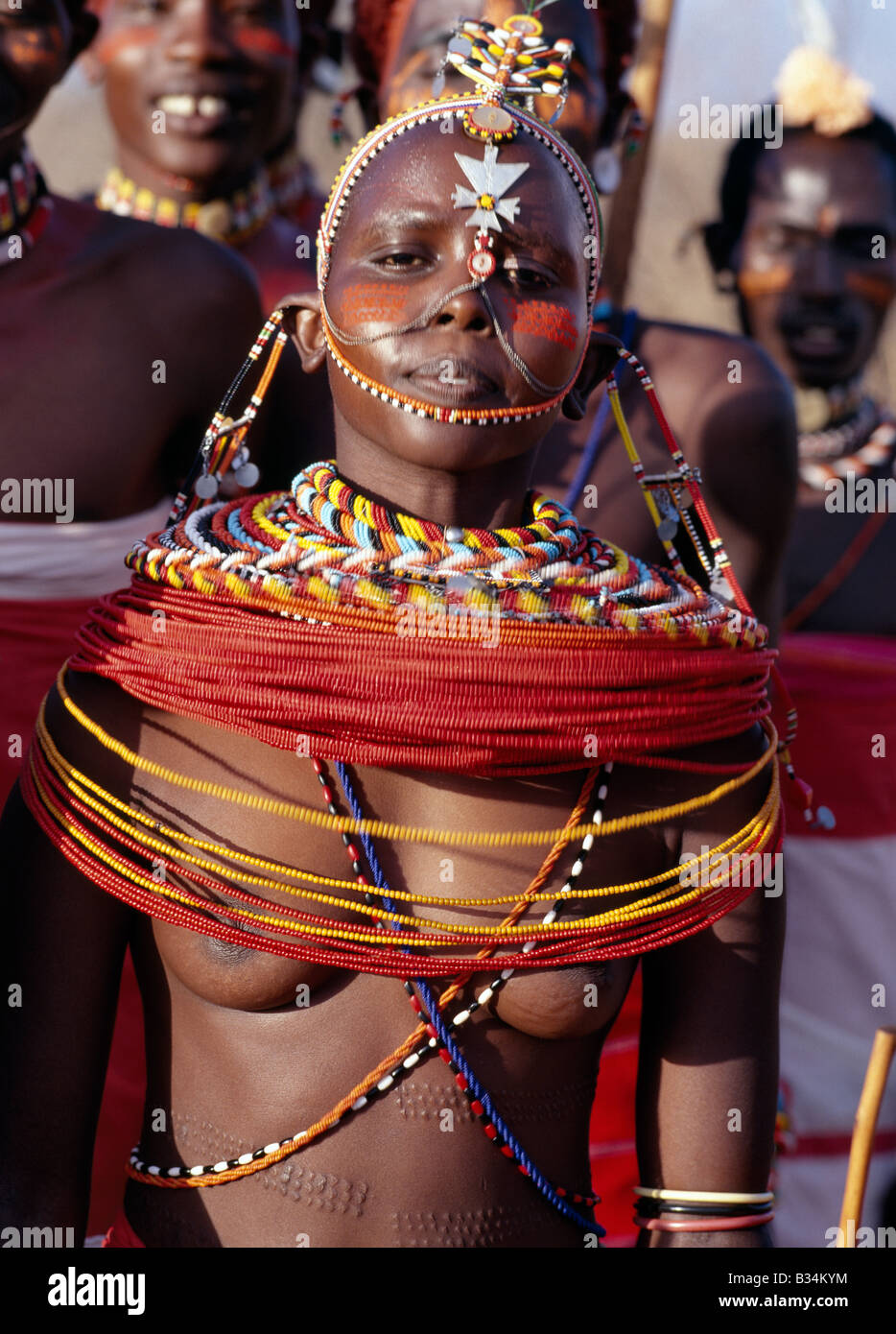 Kenya, Samburu district, Kirimun. A pretty Samburu girl dances with warriors of her tribe.Girls arch their backs and by thrustin Stock Photo