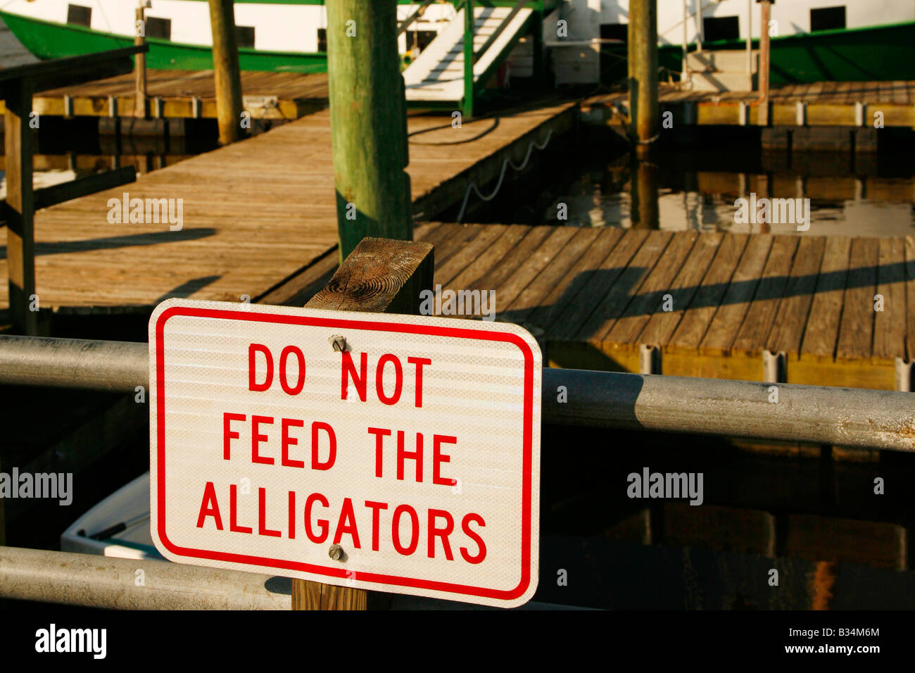 "Do not feed alligators" sign on pier for historic sailboat, Historic