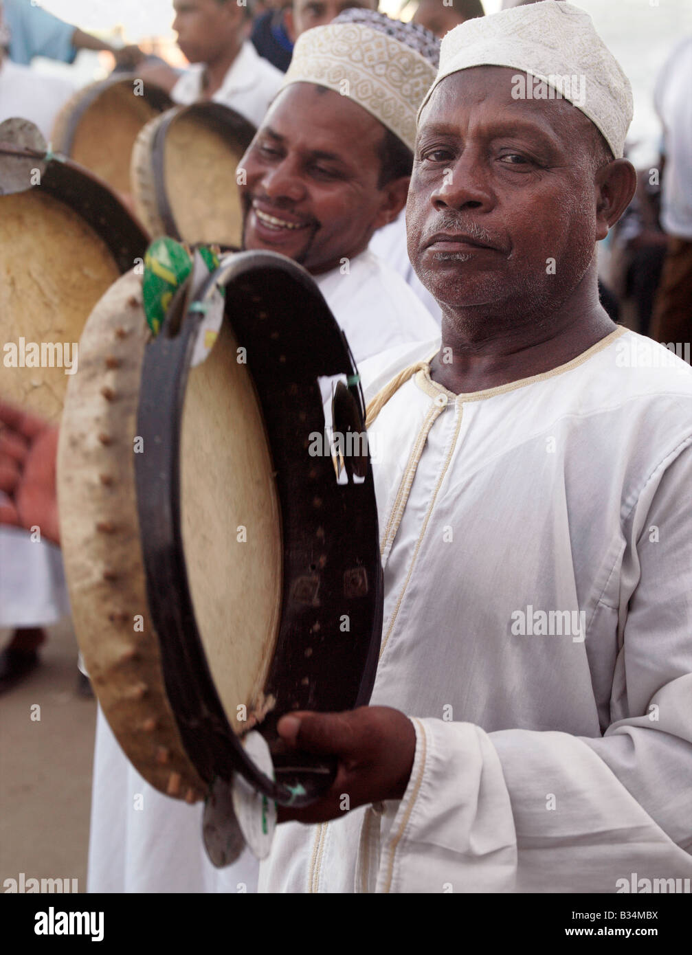 Kenya, Coast Province, Lamu Island. Muslim men maintain rhythm with tambourines during a performance of the Shabuwani along the Stock Photo