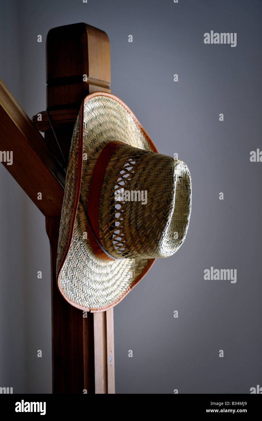 straw hat hanging on wooden banister post Stock Photo