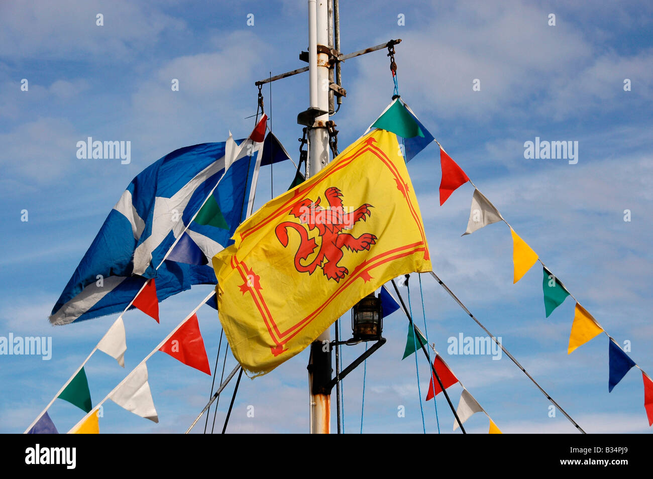 The lion rampart and Saltire flag - Scottish - blow in the wind from a mast of a boat. Stock Photo