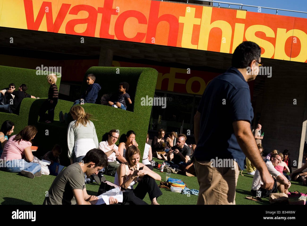 People sit on large fake grass chairs in London, UK Stock Photo