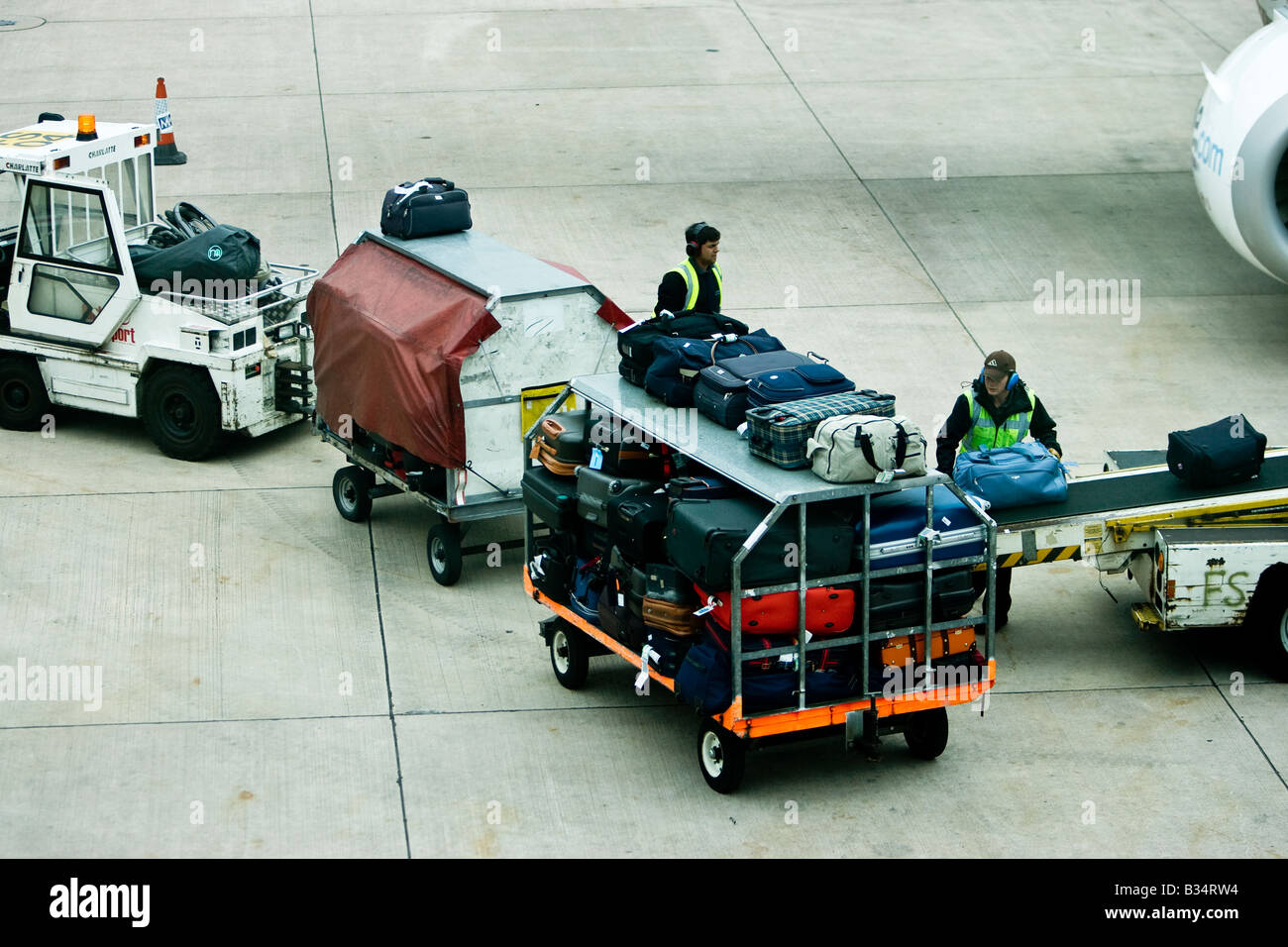 Baggage handler moveing luggage onto aircraft airport air side UK GB