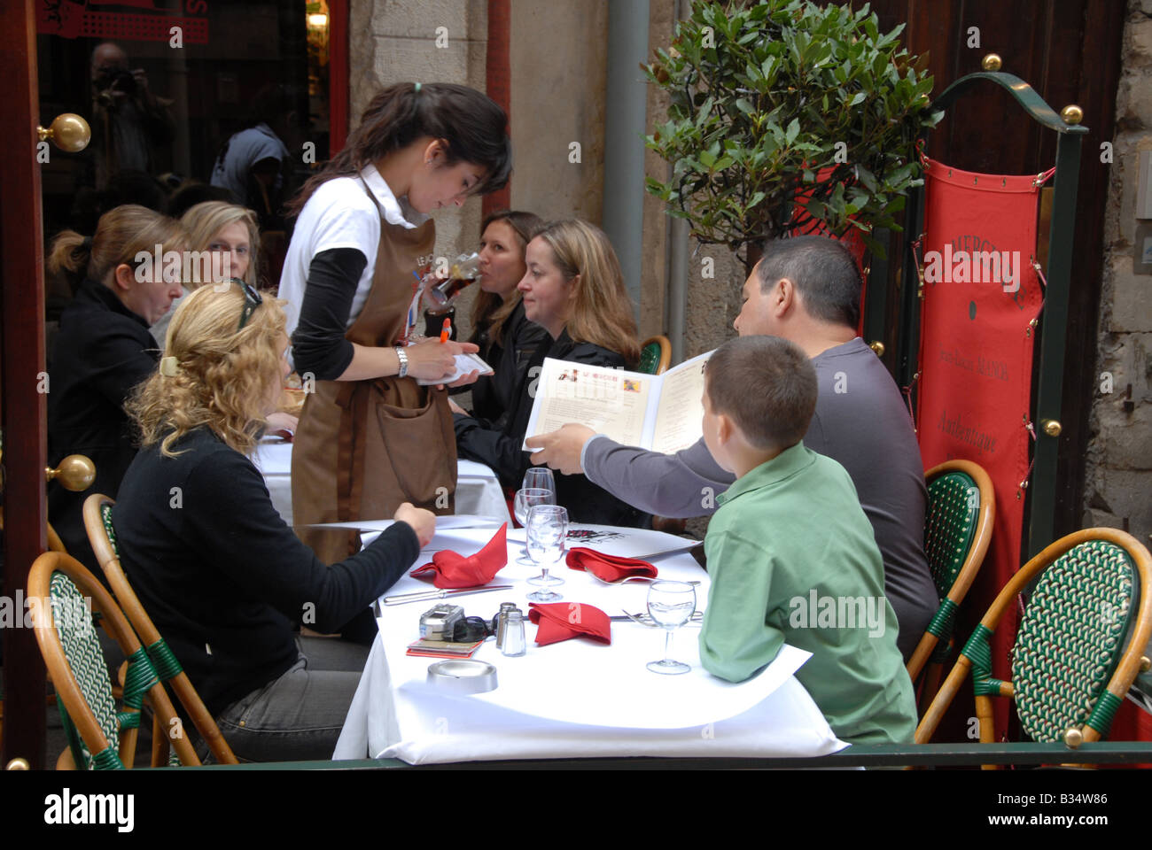 A waiter taking a lunch order from a family in one of the restaurants in Rue Merciere, Lyon,France Stock Photo