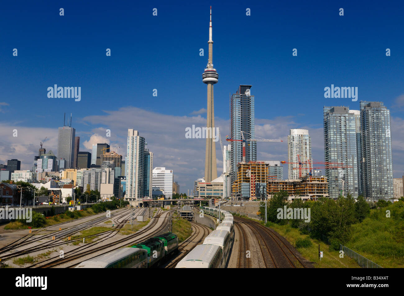 GO trains leaving on rail corridor for end of work commute from downtown Toronto with highrise towers and CN Tower Stock Photo