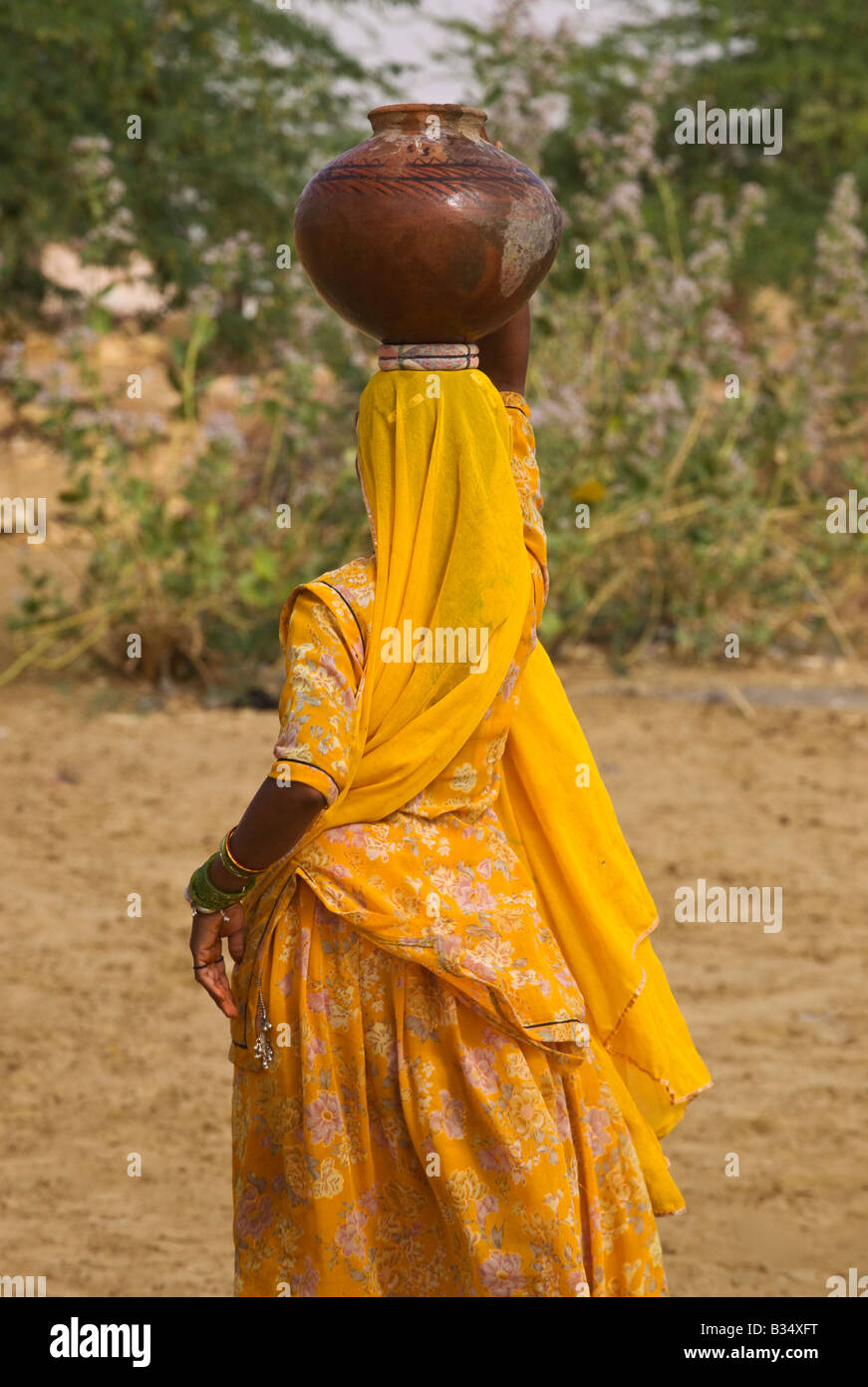 A BANJARI TRIBESWOMAN carries water in her village in the THAR DESERT near JAISALMER RAJASTHAN INDIA Stock Photo