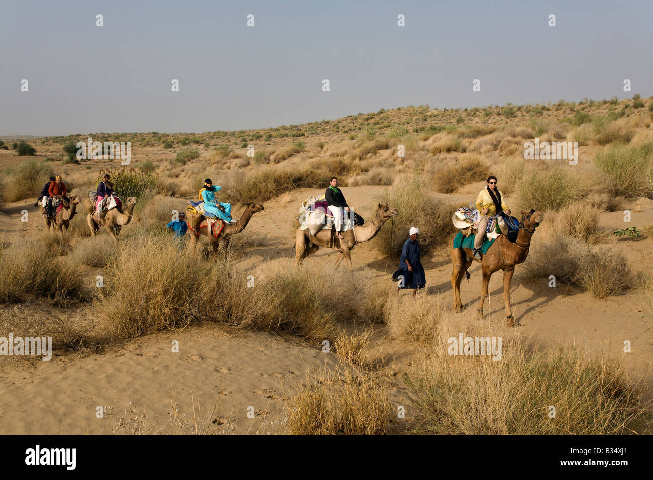 Tourists ride CAMELS in the THAR DESERT near JAISALMER RAJASTHAN INDIA MR Stock Photo