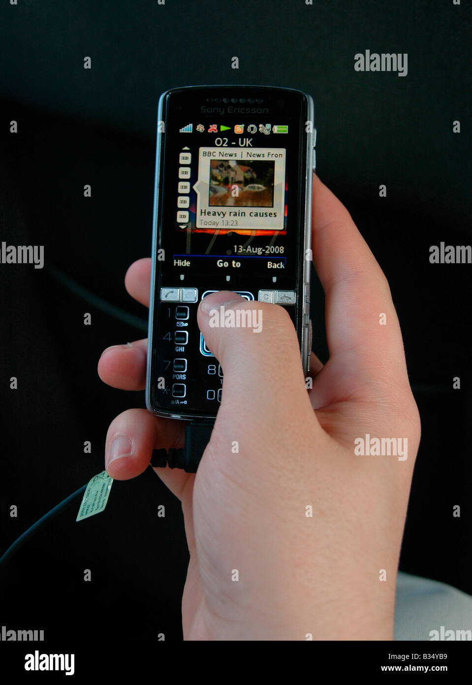 A close up of a hand and  screen of a PDA showing the weather forecast of the UK - floods. Stock Photo