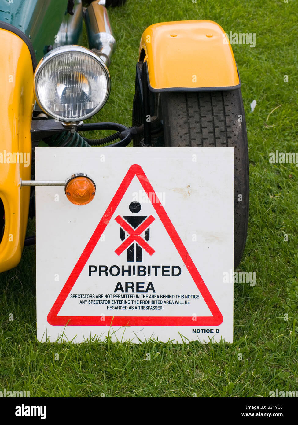 A Spectators Prohibited notice used in motor sport against the front wheel of a yellow Caterham 7 sports car Stock Photo
