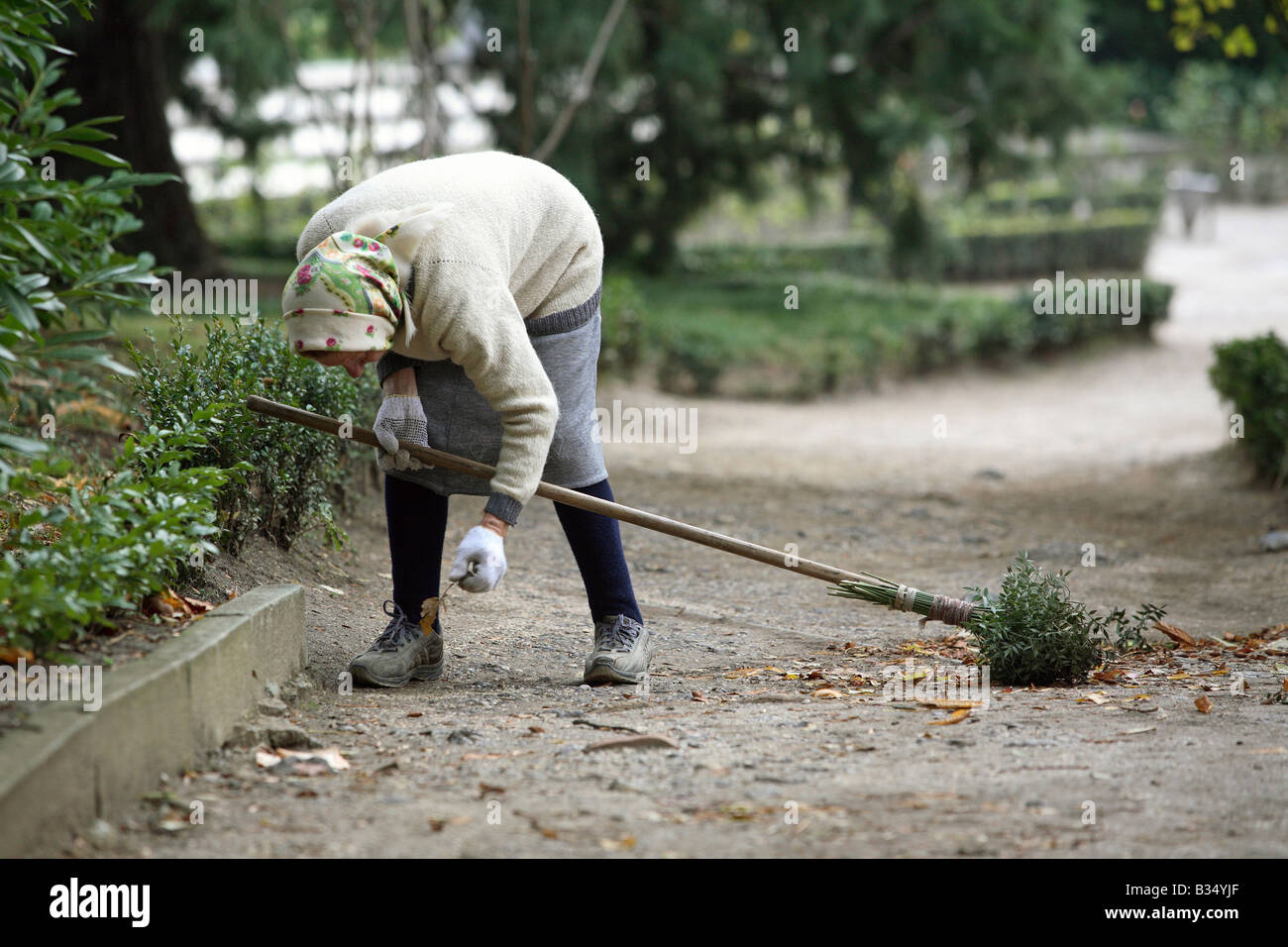 Old woman sweeping a park alley, Yalta, Ukraine Stock Photo