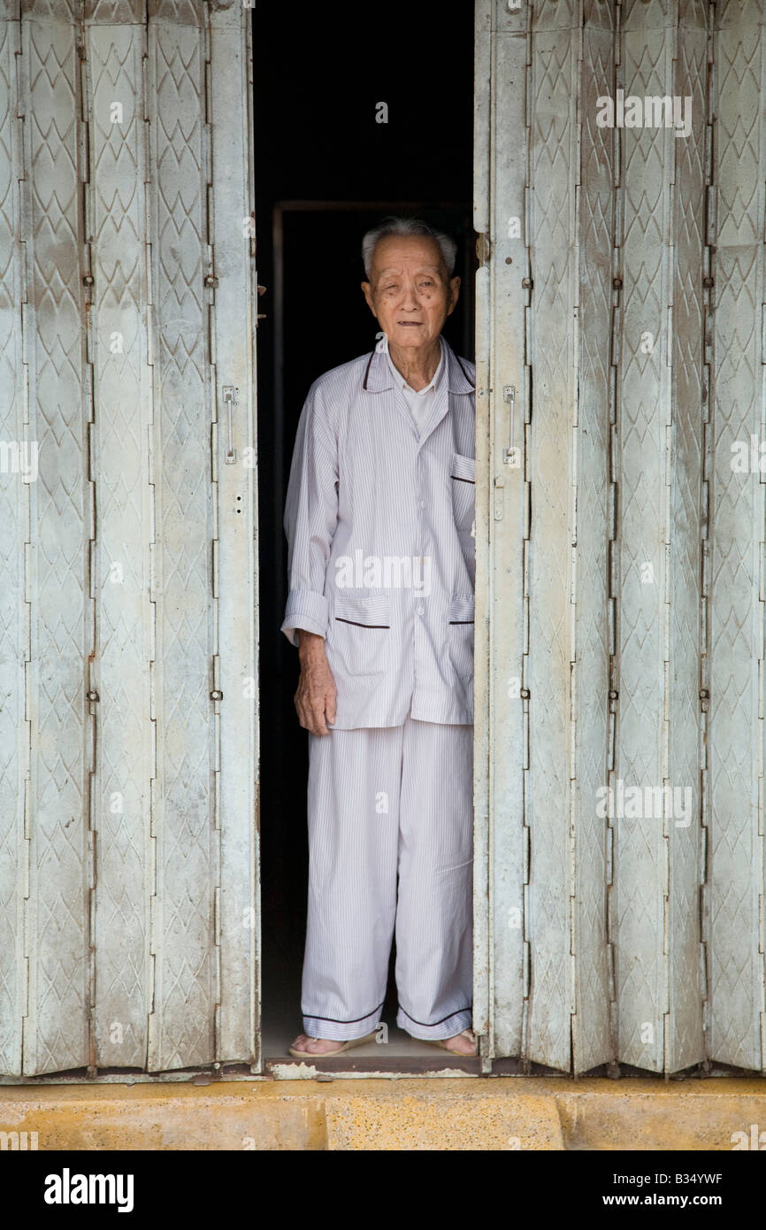 A Vietnamese man stands in the ornate doorway of his house Stock Photo