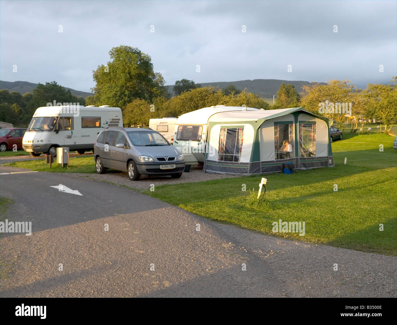 A caravan with an awning and a large motor caravan in the background on a holiday camp site in Scotland Stock Photo