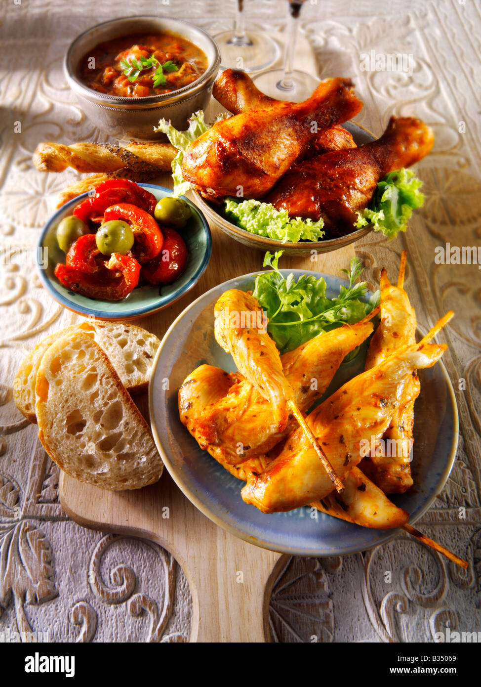 party food - From Front - Marinated chicken skewers, Marinaded chicken drum sticks and sun blushed tomatoes. Stock Photo