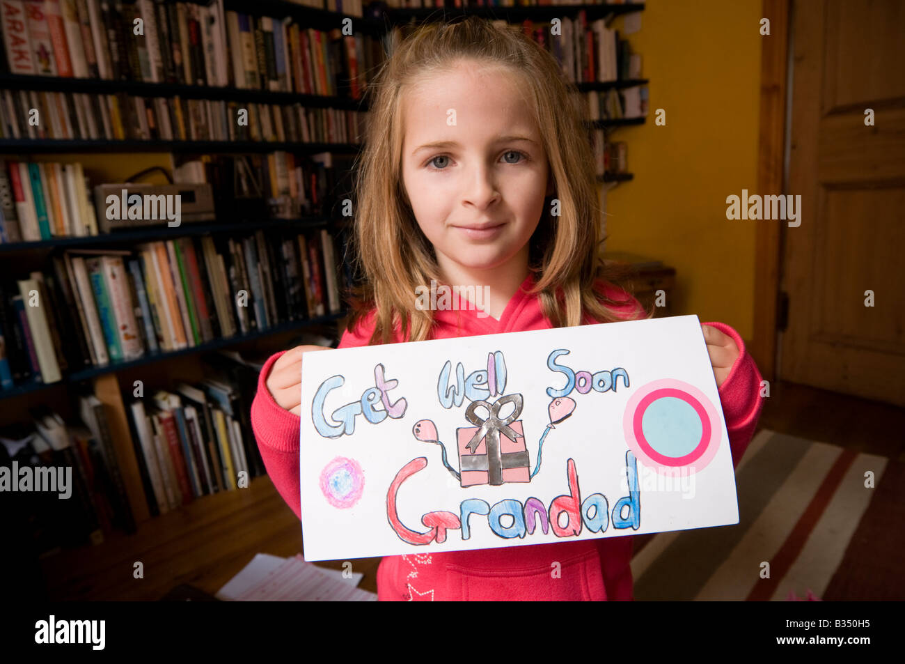 Ten year old girl holding a home made hand made Get Well Soon Grandad card UK Stock Photo