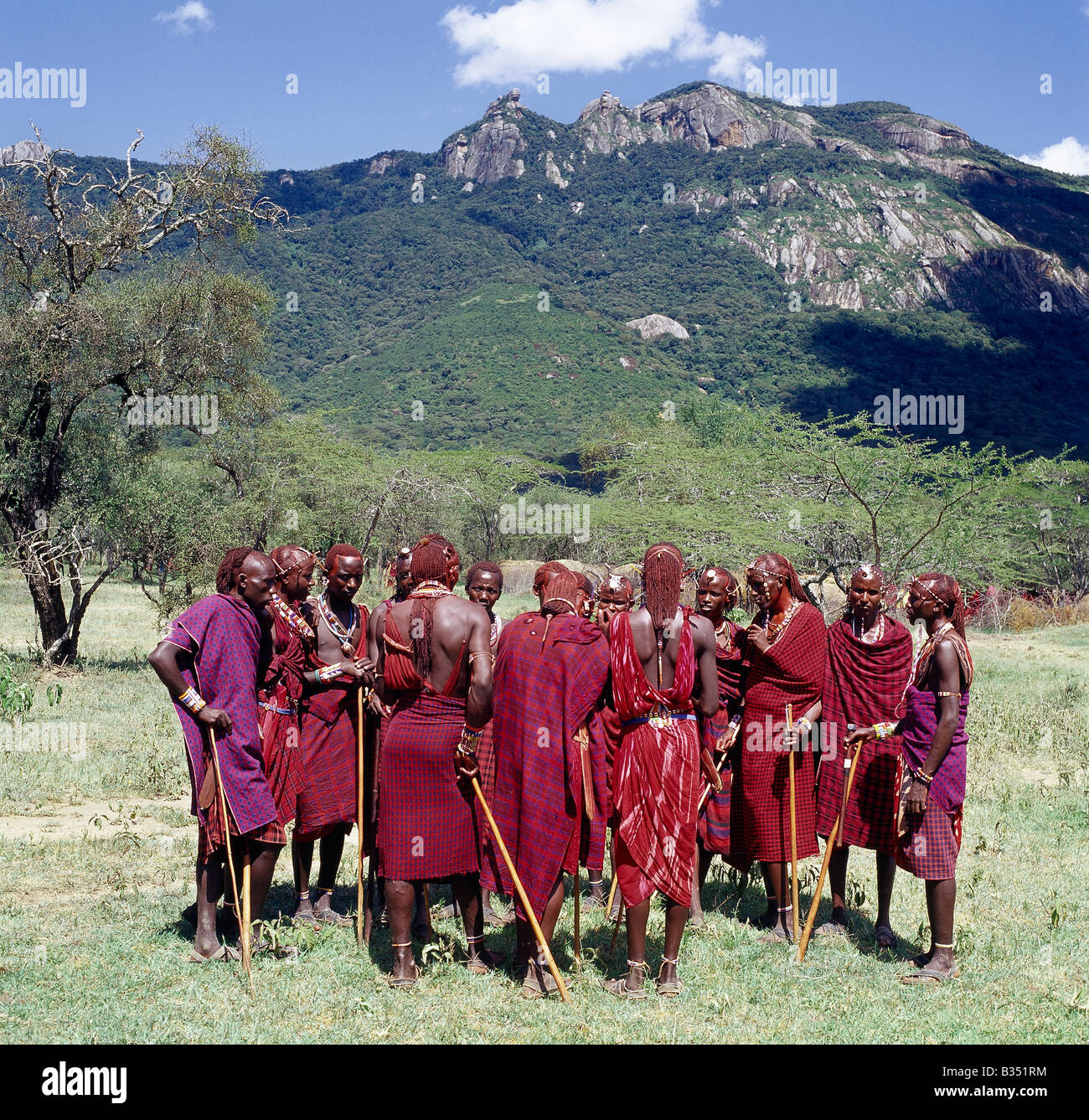Kenya, Kajiado, Ol doinyo Orok. A group of Maasai warriors, resplendent with long Ochred braids, chat beneath Ol doinyo Orok, the black mountain. Stock Photo