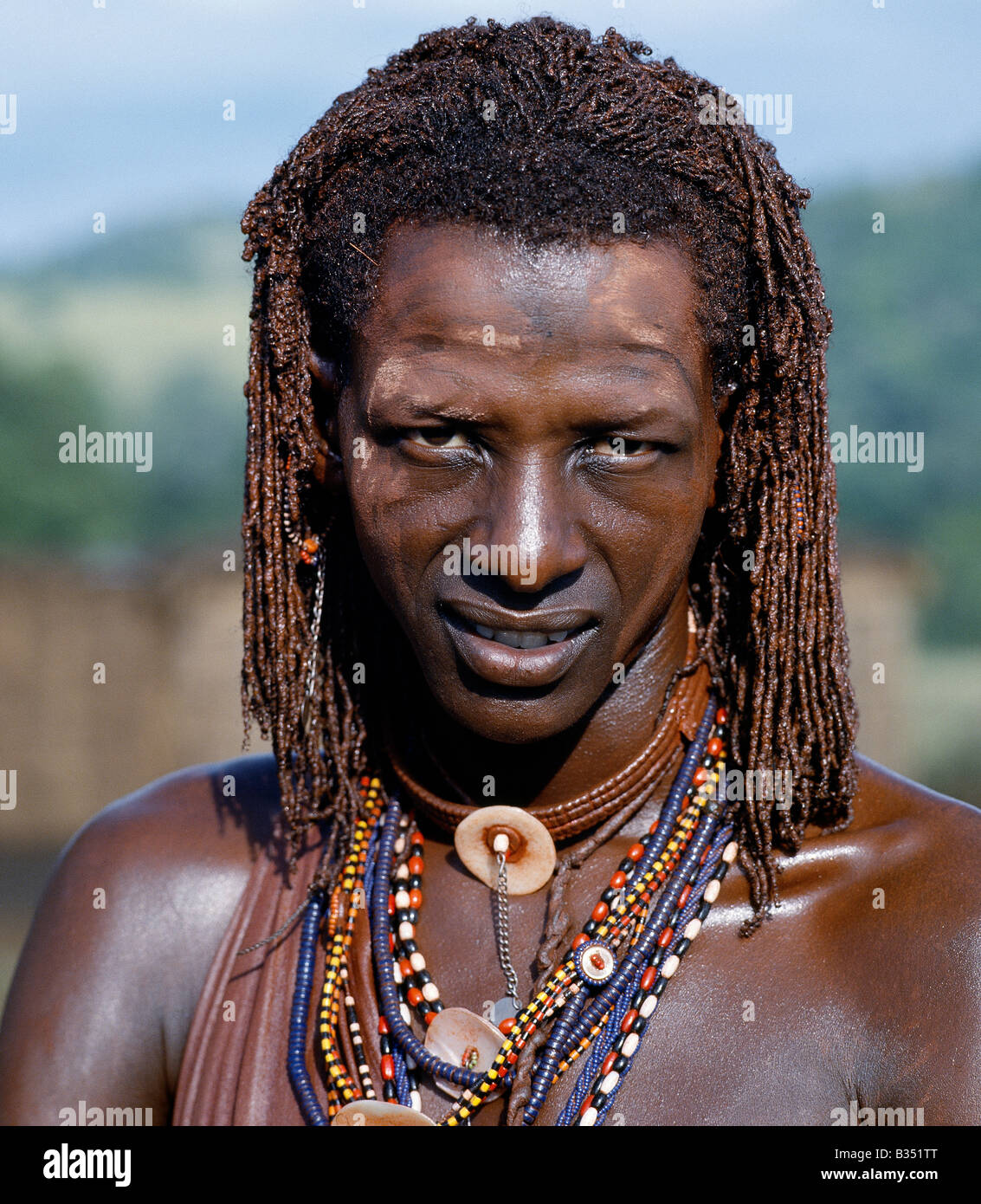 Kenya, Trans-Mara, Lolgorien. A Maasai warrior resplendent with long ochred braids. His body has been smeared with red ochre mixed with animal fat while parts of his face have been covered with ochre powder. Stock Photo