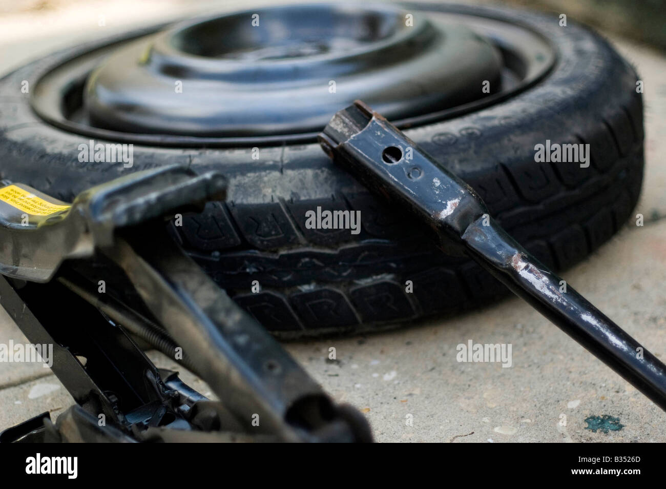 spare tire for a car, jack, and tire iron on the ground Stock Photo