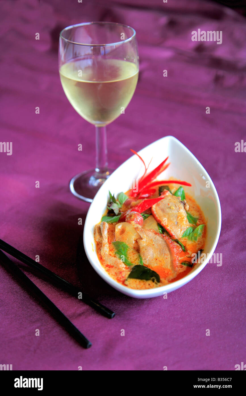 Thai Food Szechuan Duck Stir Fried fresh vegetables meal chopsticks glass of white wine in a restaurant setting Stock Photo
