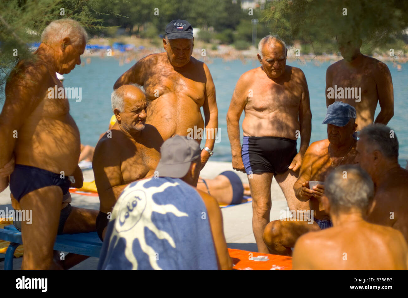 Old men play cards on Split city beach Croatia Stock Photo