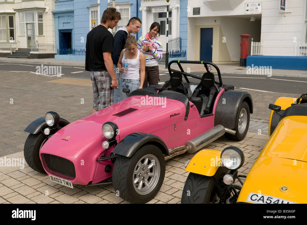 four young people with Lotus Caterham 7 classic british motor car supporters club rally on the promenade in Aberystwyth Wales UK Stock Photo
