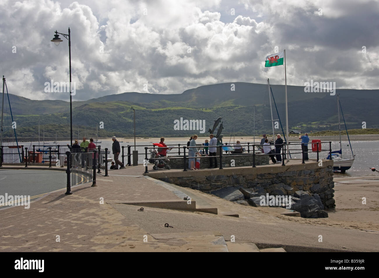 tourist relaxing around a sculpture of dolphins on barmouth harbour Stock Photo