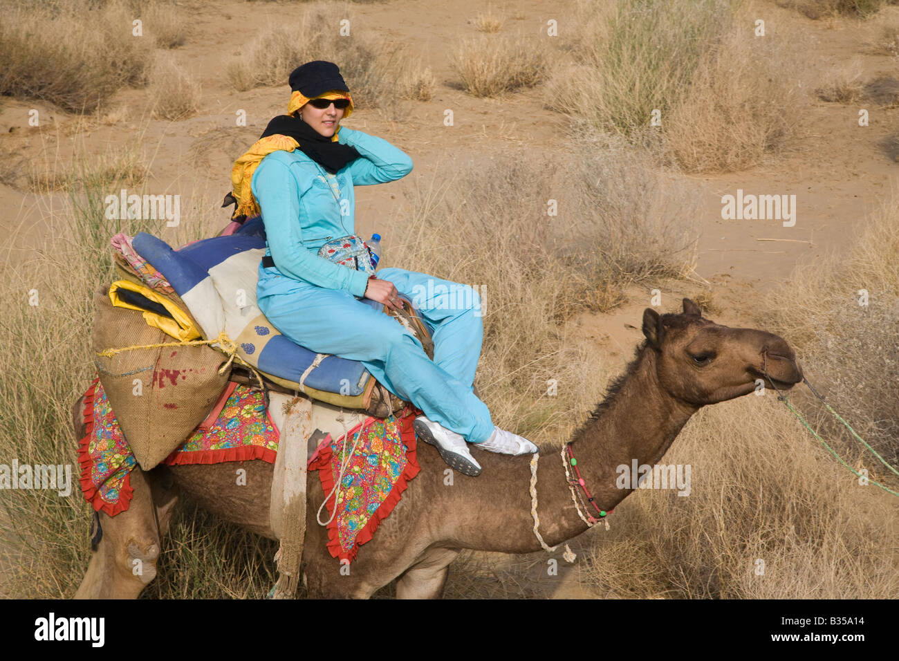 A FRENCH WOMAN rides a CAMEL in the THAR DESERT during a SAFARI near JAISALMER RAJASTHAN INDIA MR Stock Photo