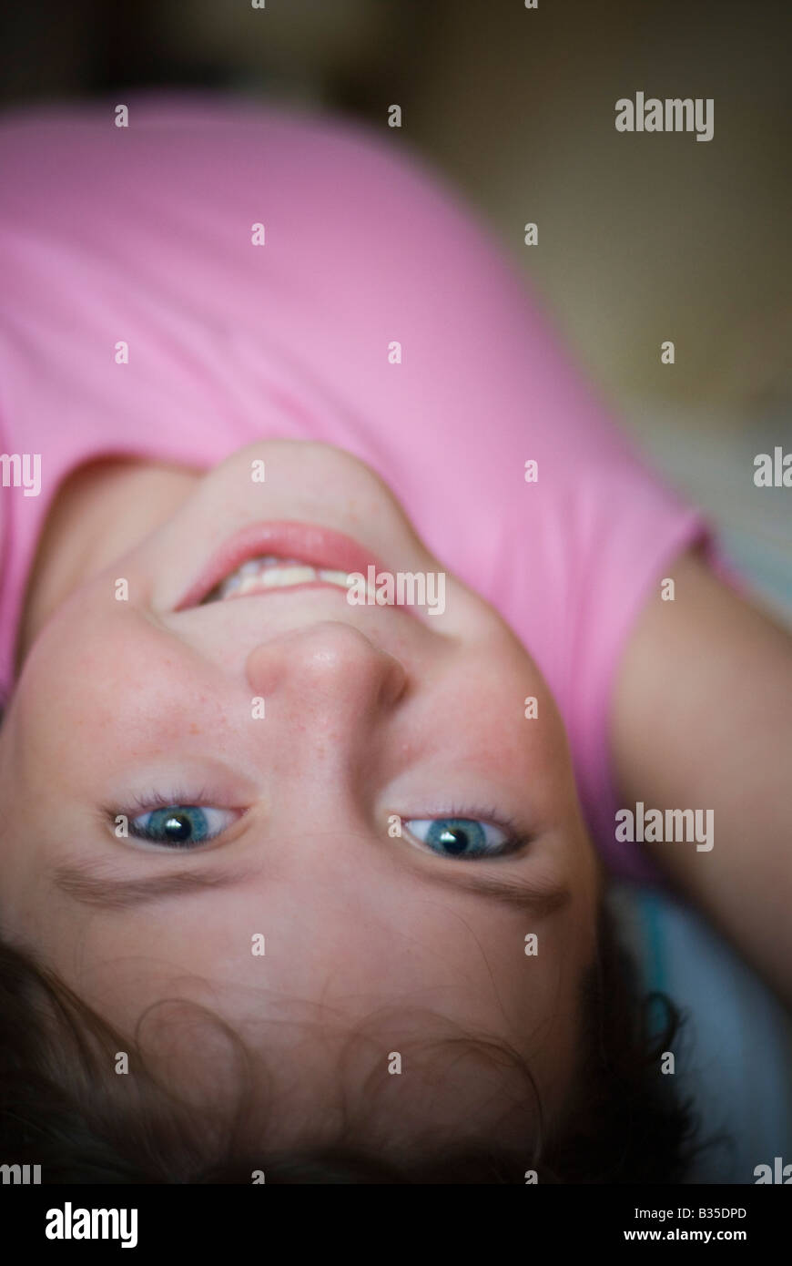 Happy young girl with blue eyes and pink t-shirt lying on her back ...