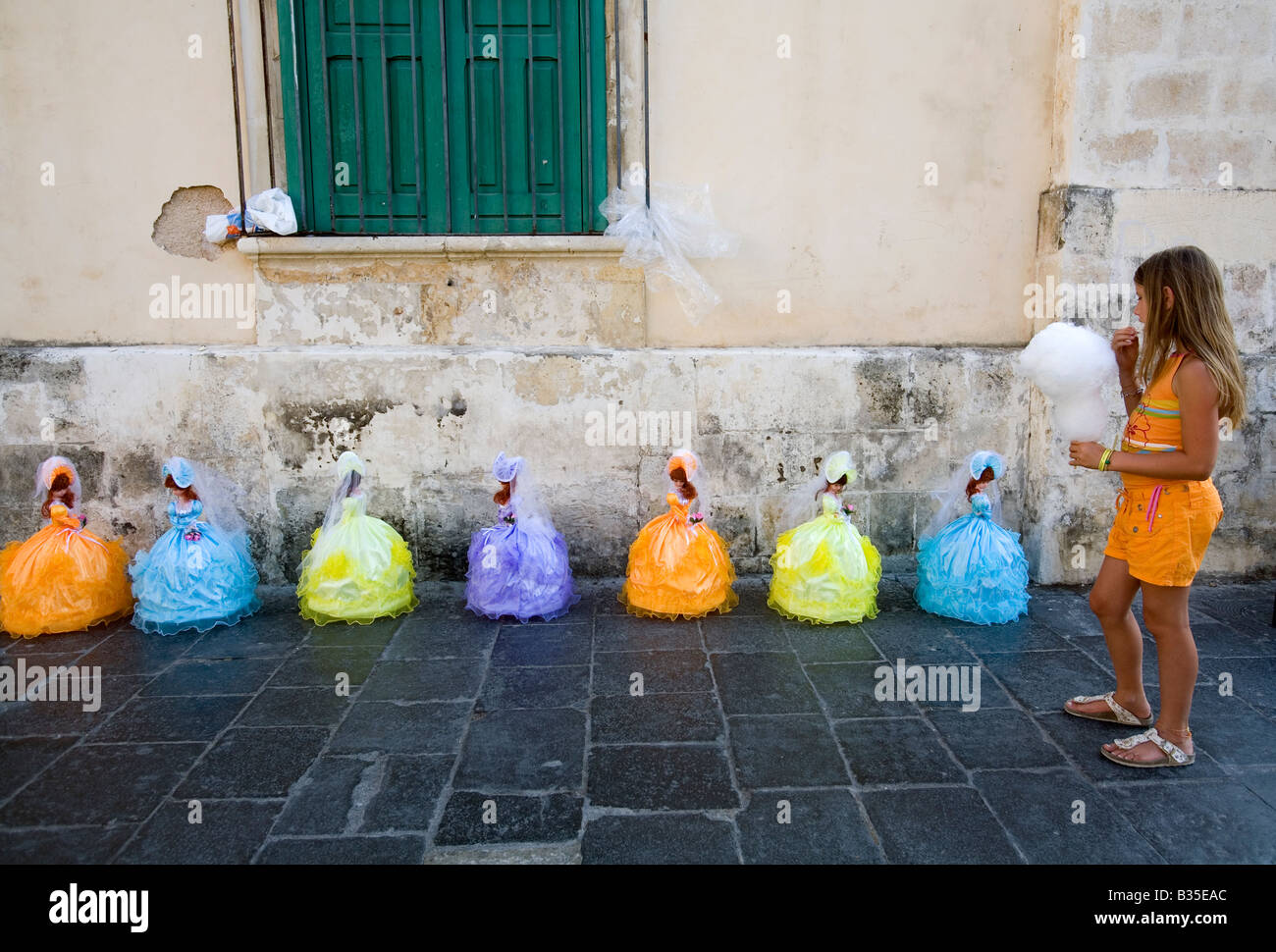 Young baby girl looking at typical local dolls for sale in the street of Noto Sicily Italy Stock Photo