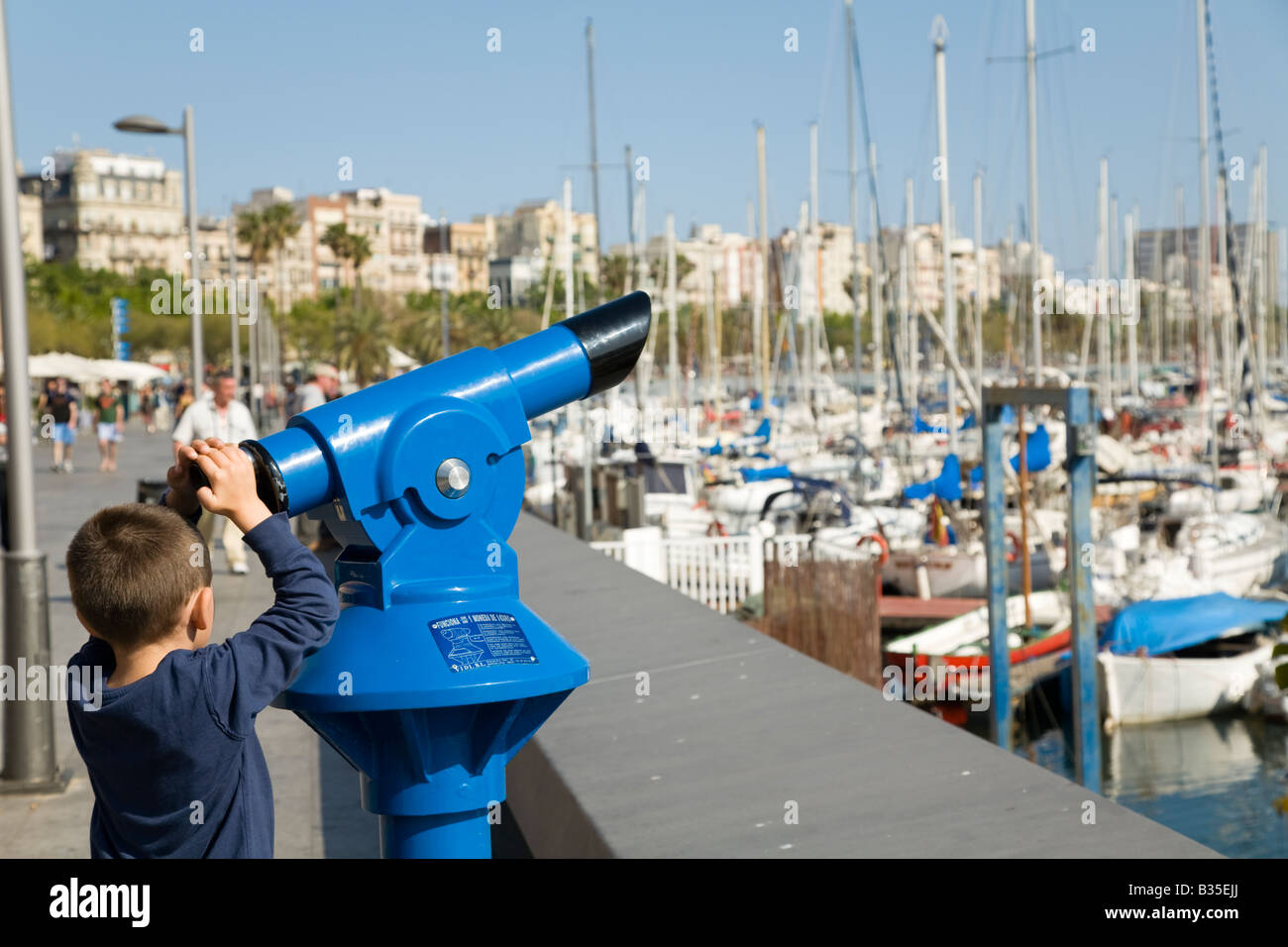 SPAIN Barcelona Young boy reach for viewing scope at Marina Port Vell sailboats docked in harbor Stock Photo