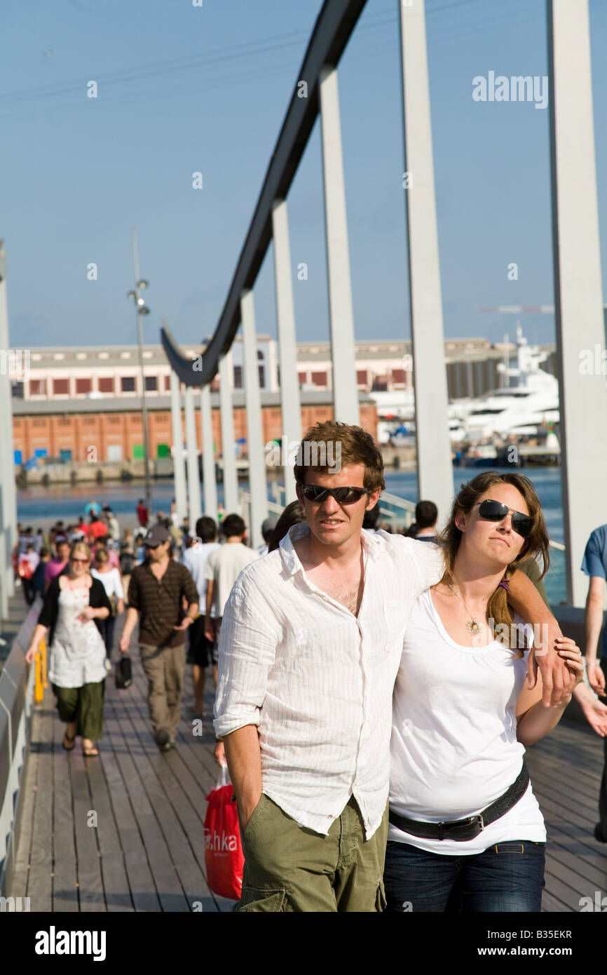 SPAIN Barcelona Young couple walk on wooden pedestrian bridge to Maremagnum mall at Marina Port Vell Stock Photo