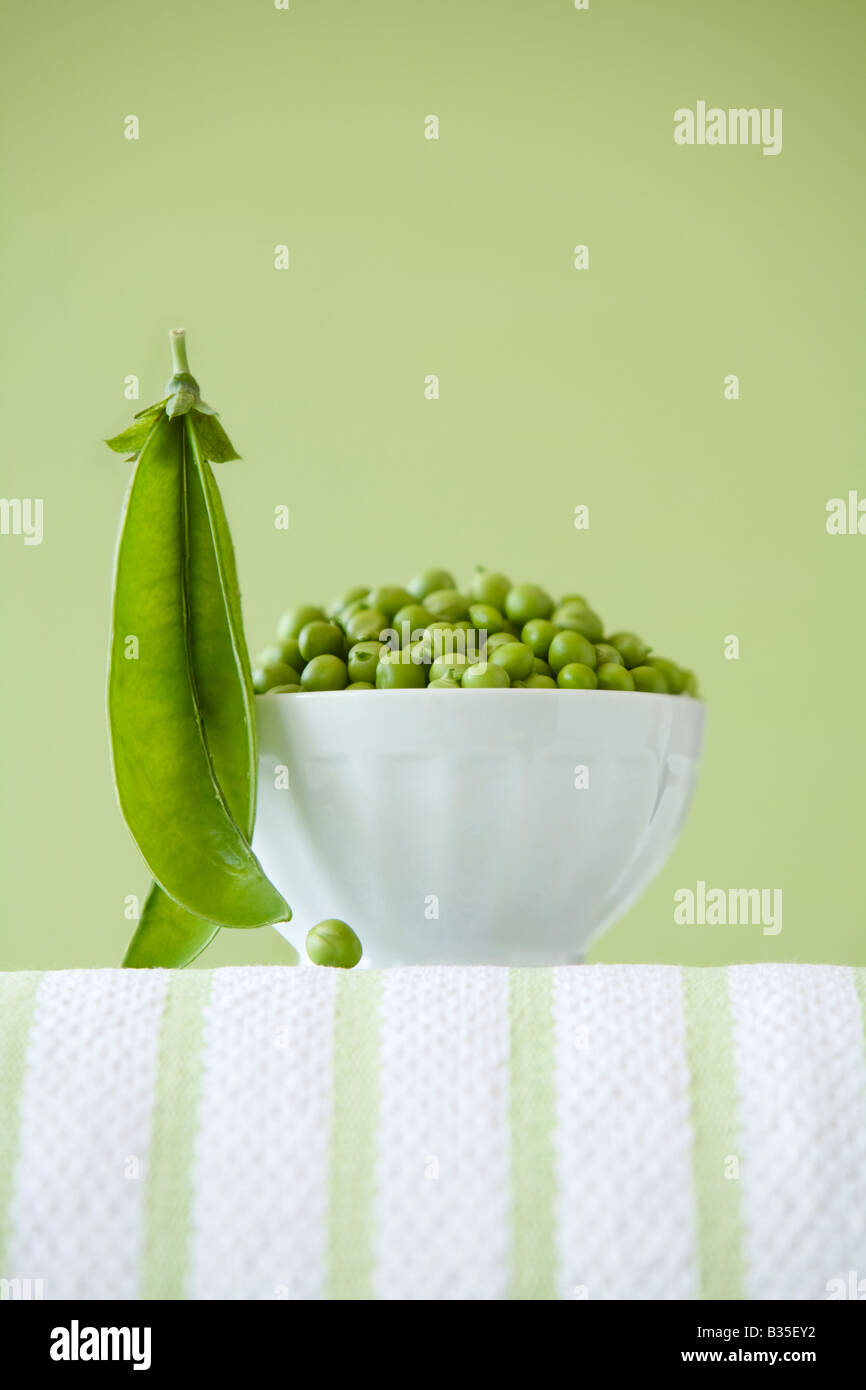 bowl of peas in white bowl with green background Stock Photo