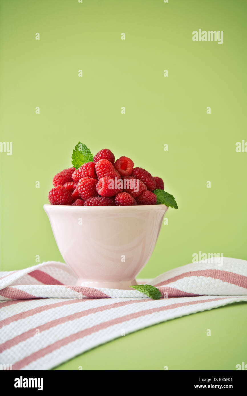 raspberries in a bowl on a green background Stock Photo