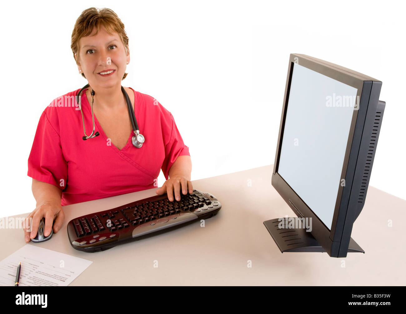 A smiling beautiful middle age nurse or doctor is sitting at her desk Stock Photo