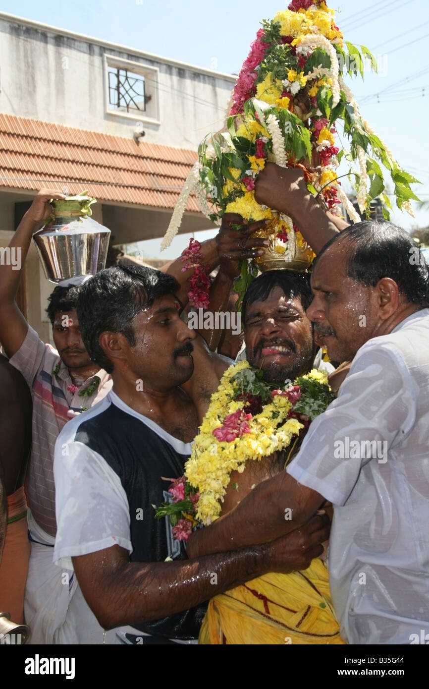 Men help Hindu devotee possessed by Kali in the form of Mariamman outside a Hindu temple , Tamil Nadu , India Stock Photo