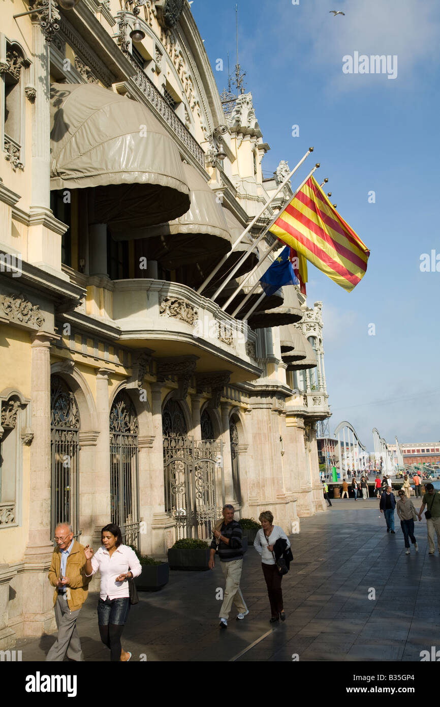 SPAIN Barcelona People walk past Port of Barcelona building along waterfront Maremagnum mall and wooden pedestrian bridge Stock Photo