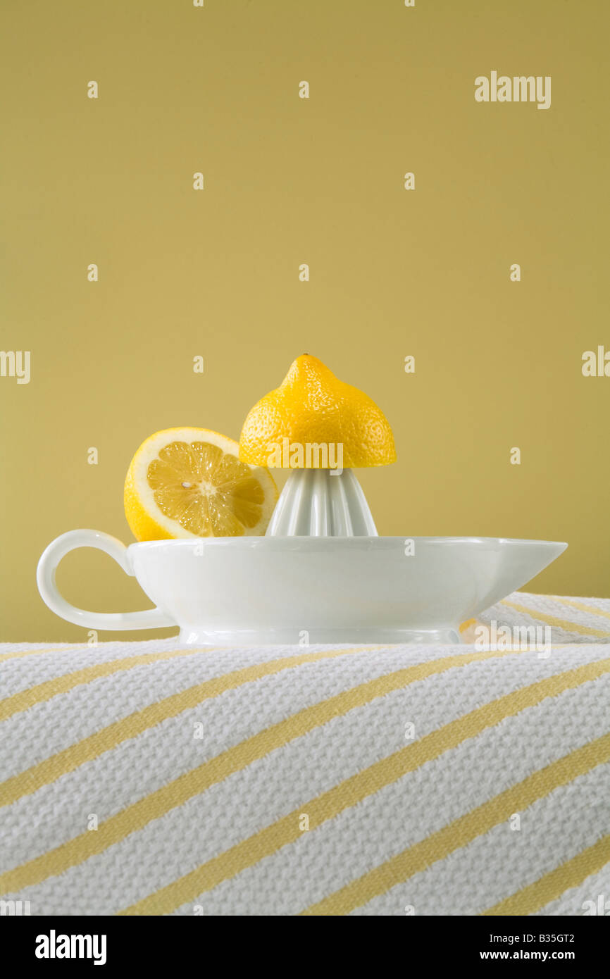 lemon on a squeezer on yellow background Stock Photo