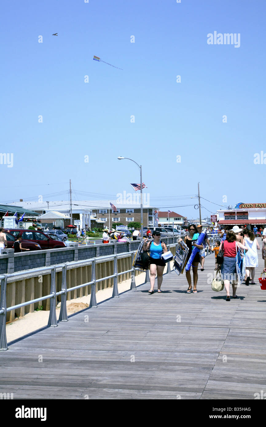 People festooned with chairs and beach towels on boardwalk Stock Photo