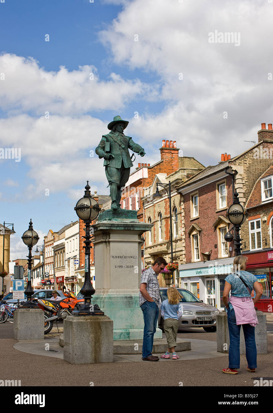 Two adults and a child, discussing Cromwell beneath his statue, Market Hill, St.Ives. Stock Photo
