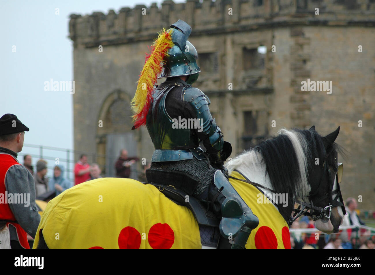 Yellow knight on horseback in front of crowds Stock Photo