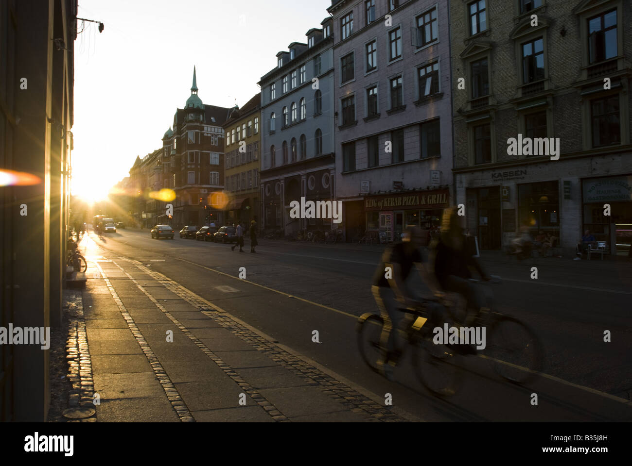 Two cyclists ride their bikes down Norrebrogade in Norrebro, Copenhagen, Denmark. Stock Photo