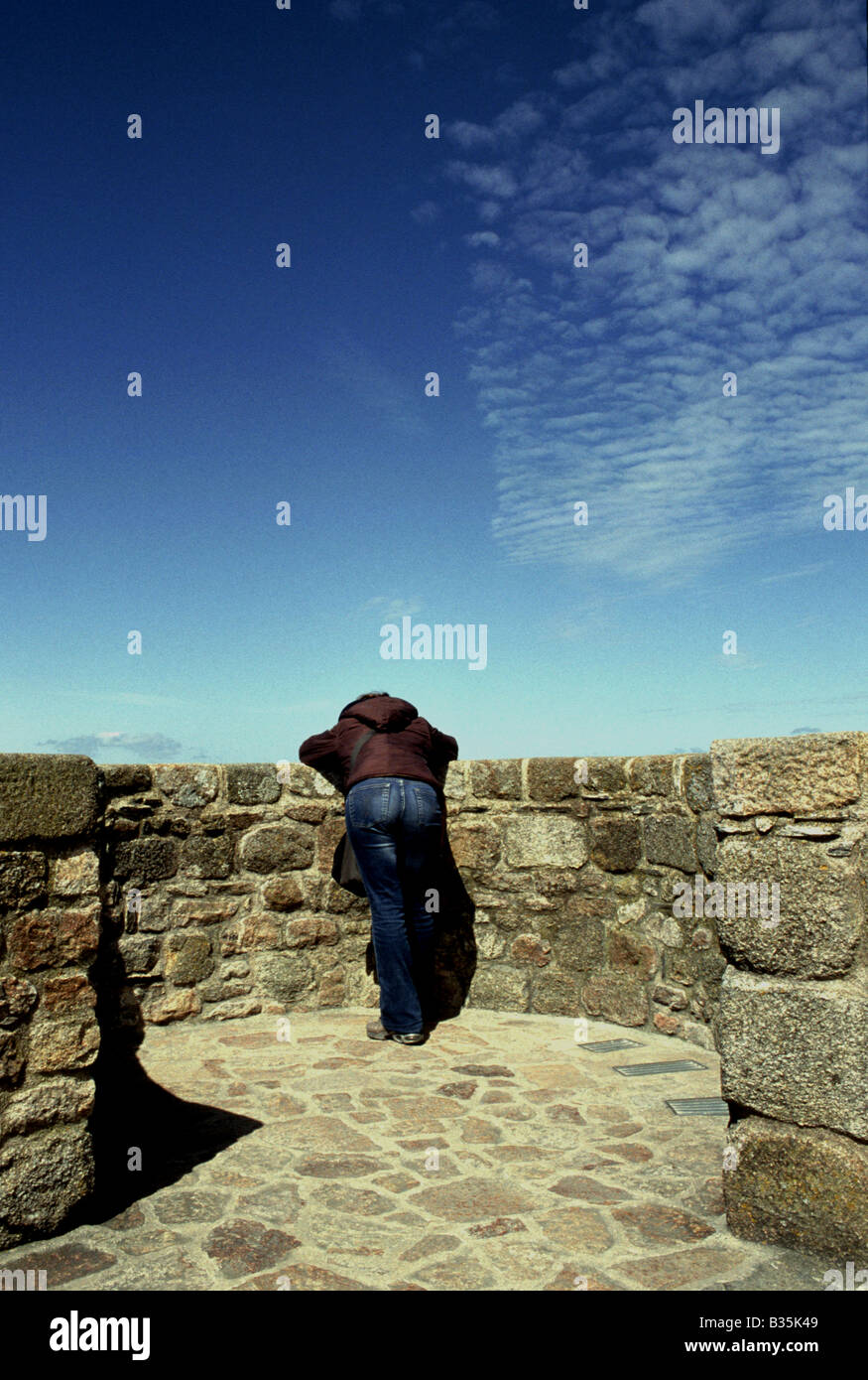 Mont Saint Michel Woman looking over old stone wall Stock Photo