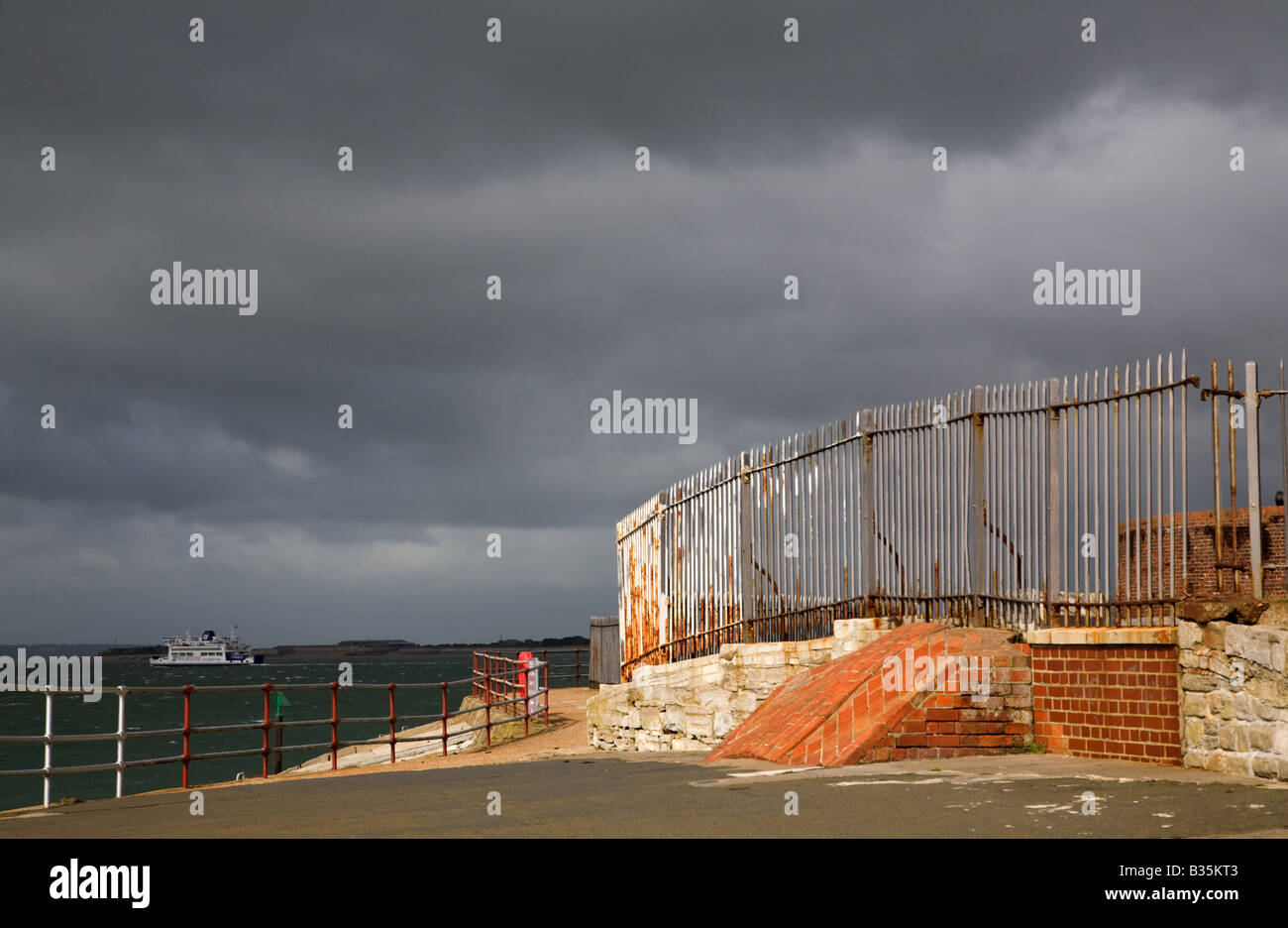 rusty and corroded railings and broken brickwork on the Portsmouth coast against a dark stormy sky Stock Photo