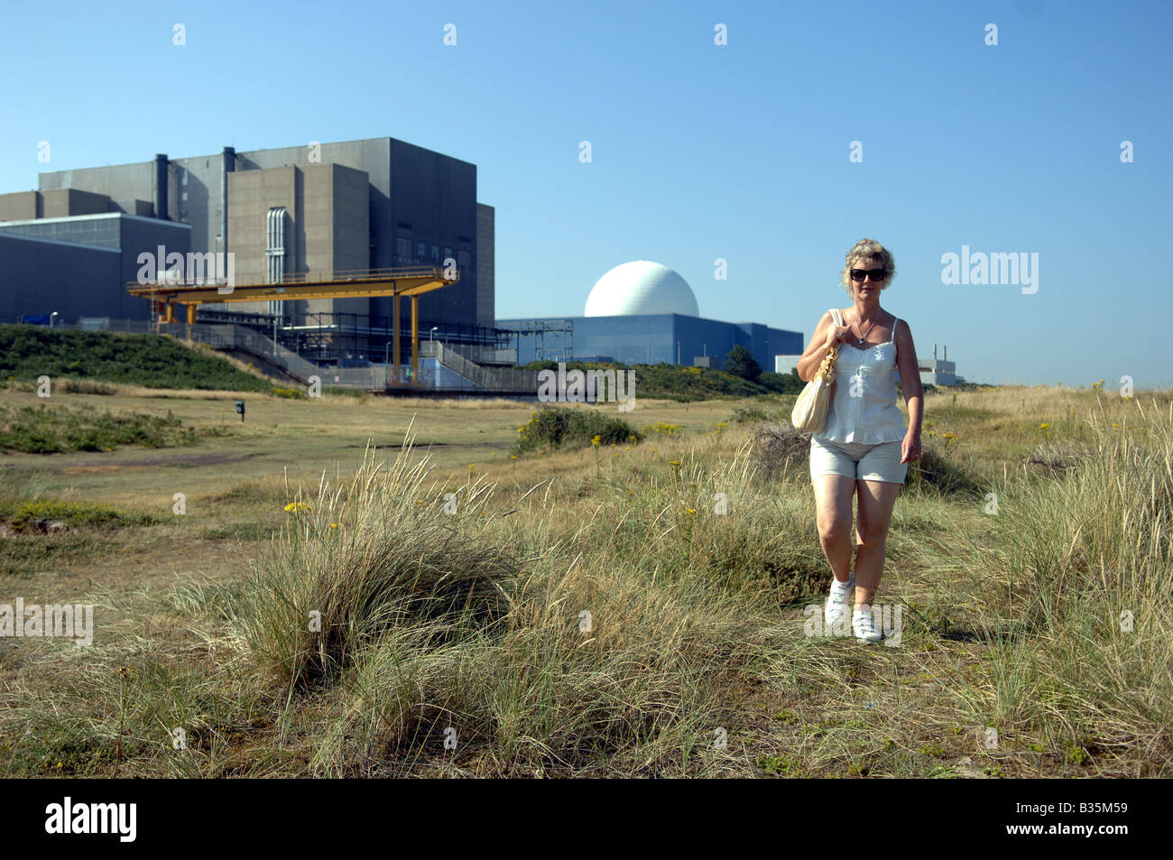 A woman walks past the Sizewell Nuclear Energy Power Station on the Suffolk coast Stock Photo