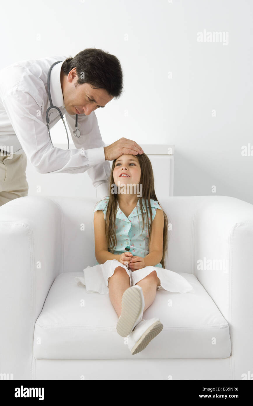 Male doctor feeling young patient's forehead, girl sitting on armchair