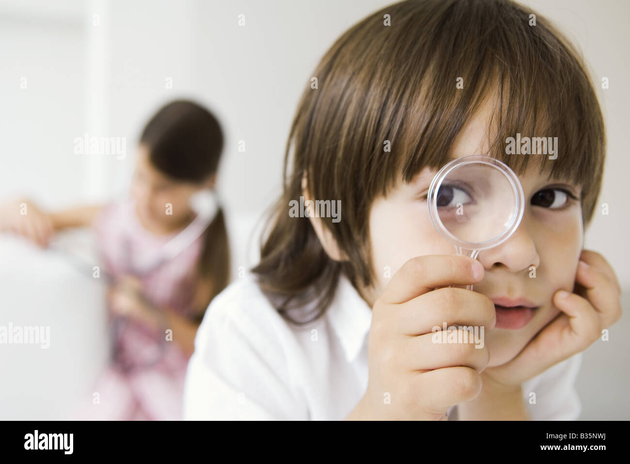 Little boy looking through magnifying glass at camera Stock Photo - Alamy