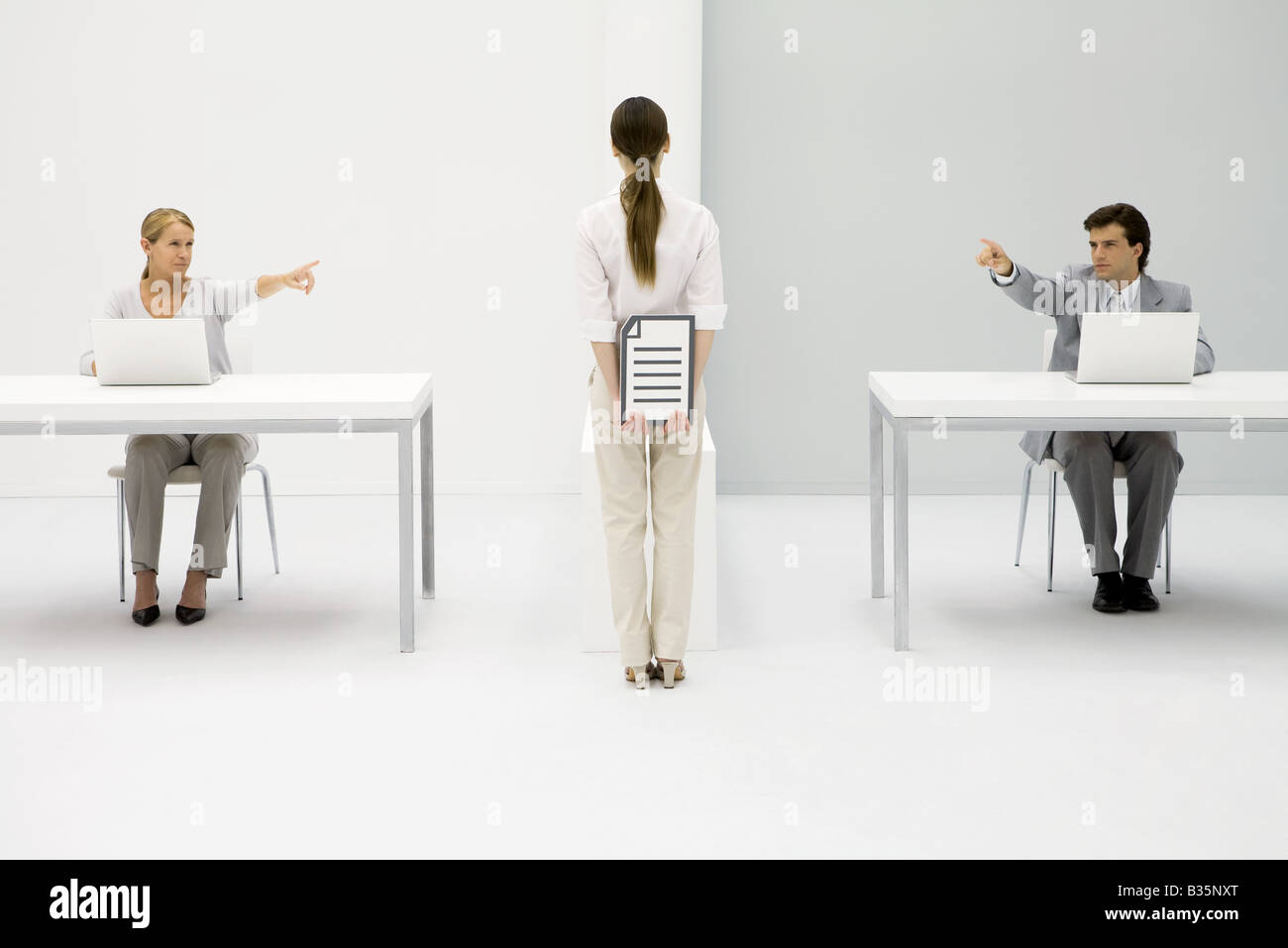 Office workers sitting at desks, both pointing at woman holding