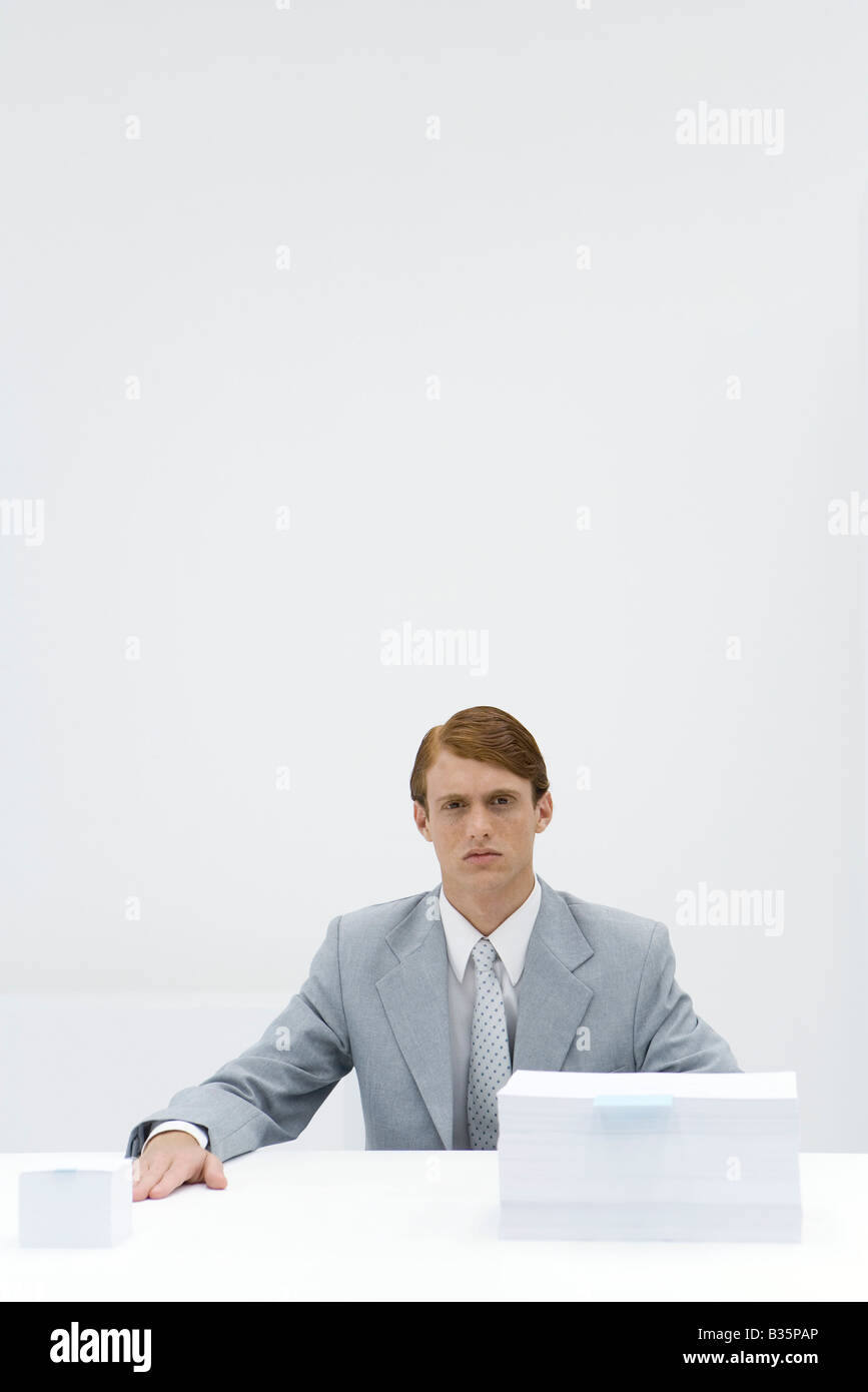 Businessman sitting at table with two different sized stacks of paper Stock Photo