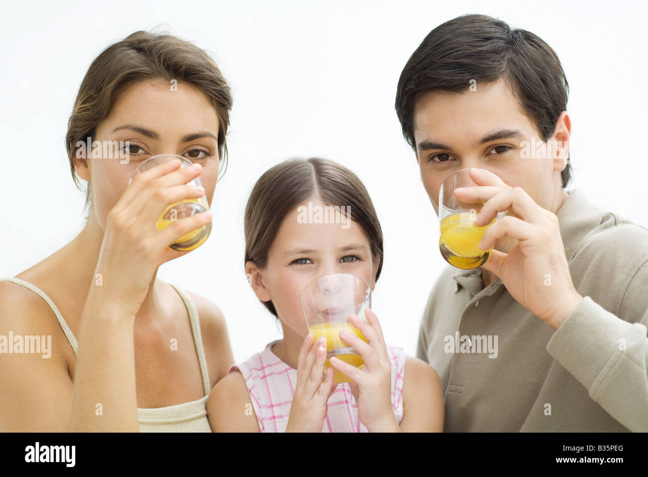 Family drinking orange juice, all looking at camera Stock Photo