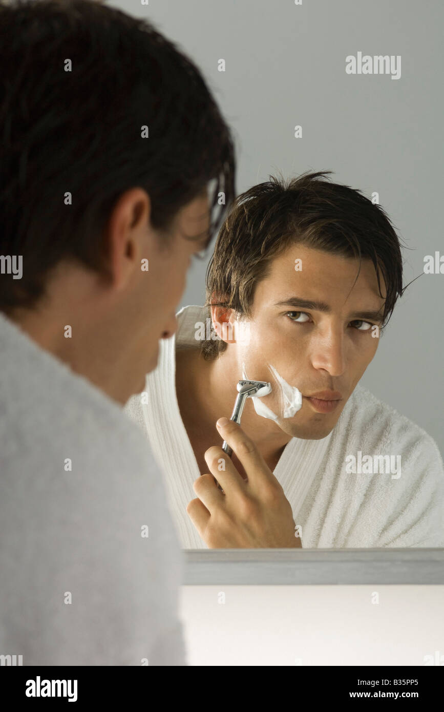 Man shaving, looking at self in mirror Stock Photo